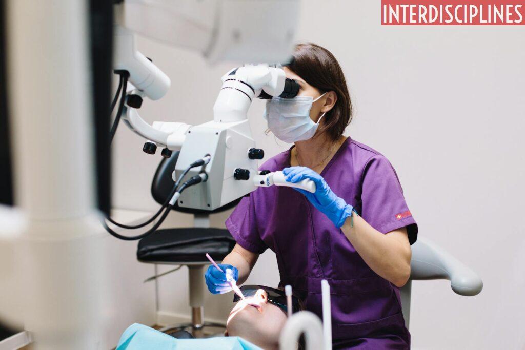 Female dentist using a microscope and modern technology during a patient examination in a dental clinic.