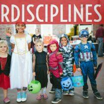 children standing while holding Jack 'o lantern and wearing costume
