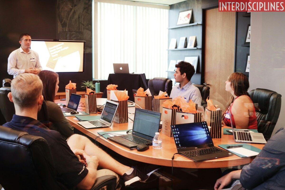man standing in front of people sitting beside table with laptop computers