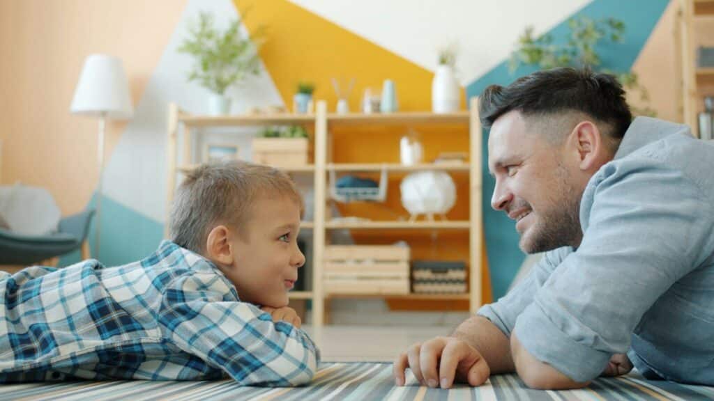 Padre e hijo hablan tumbados en el suelo, un ejemplo de disciplina positiva basada en la conexión